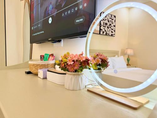 a room with a table with flowers and a tv at Huko House in Ho Chi Minh City