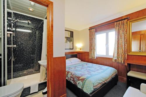 a bedroom with a bed and a shower and a sink at London Visitors Hotel in London