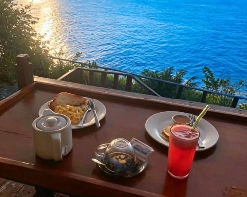 a table with two plates of food and a drink at Sea Cliff Eco Nusa Penida in Polilit