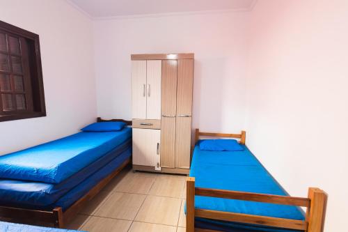 a bedroom with two beds and a cabinet at Sinuca, churrasqueira e fogueira a 300 metros do mar in Itanhaém