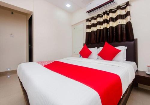 a bedroom with a large bed with red pillows at Hotel Cliff Hanger in Mumbai