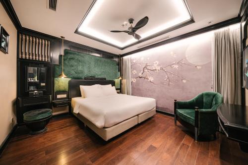 a bedroom with a bed and a green chair at Bay Luxury Fortune Grand Hotel in Hanoi