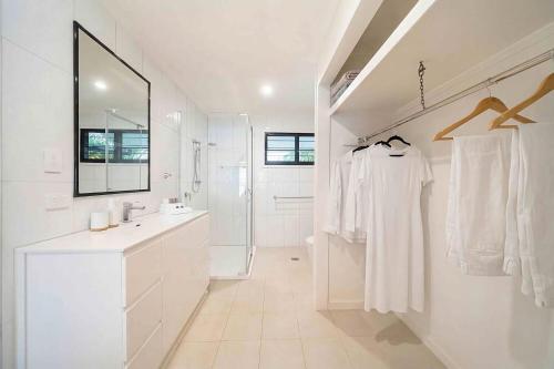 a white bathroom with a sink and a mirror at Serenity Sands in South Mission Beach
