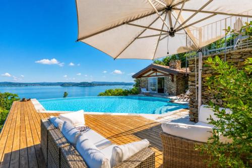 a house with a swimming pool and an umbrella at Paradis Relais Infinity Pool Lake View in Belgirate