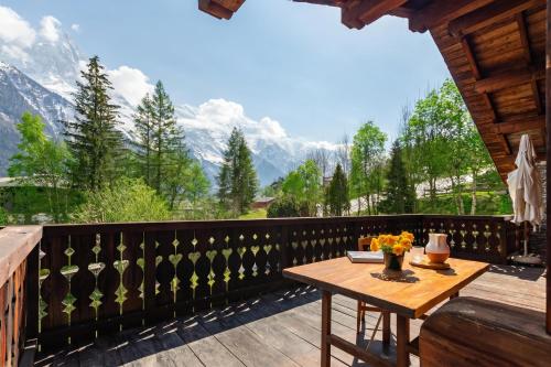 a table on a balcony with a view of mountains at Chalet du Brevent ski in - ski out - Happy Rentals in Chamonix