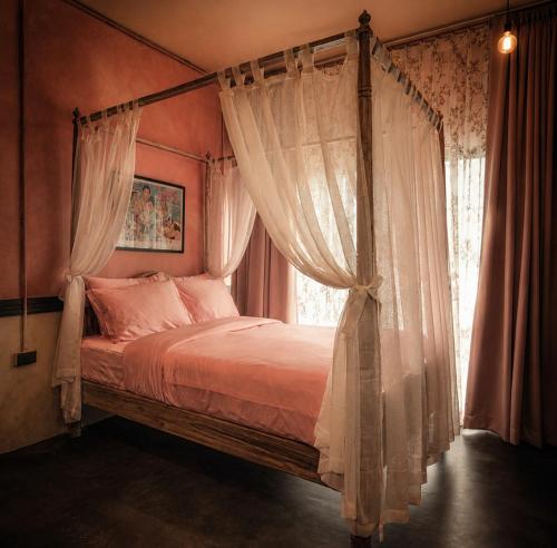 a bedroom with a canopy bed with curtains and a window at Cinematique Boutique Cinema Hotel in Bangkok