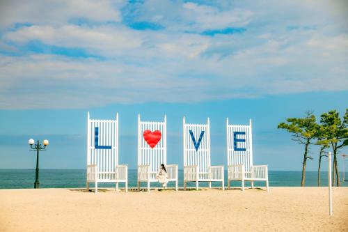 a woman sitting inront of white chairs on the beach at Kensington Resort Seorak Beach in Sokcho