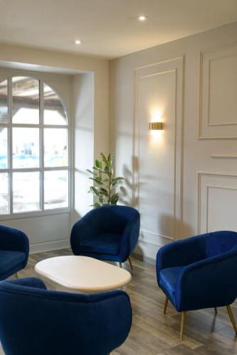 a waiting room with blue chairs and a table at Hôtel Les Comtes de Pardiac in Marciac