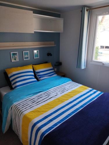 a blue and yellow bed in a bedroom with a window at Mobil home 3ch, clim, bord de mer in Seignosse