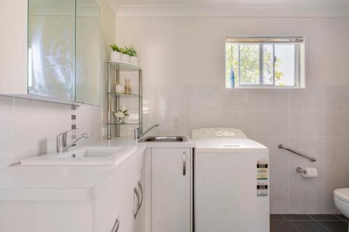 a white bathroom with two sinks and a toilet at Kingscliff Spacious Beach Cottage in Kingscliff