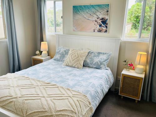 a bedroom with a bed and two windows at Kingscliff Spacious Beach Cottage in Kingscliff