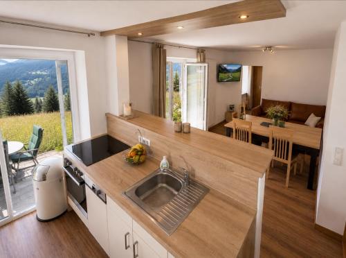 a kitchen with a sink and a living room with a table at Apartmenthaus Ahorn in Mittelberg