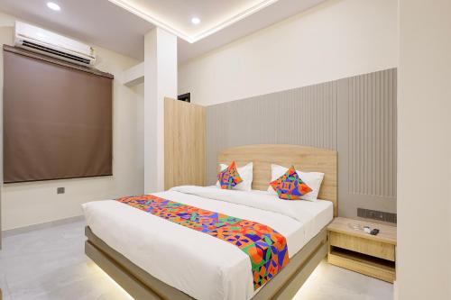 a bedroom with a large white bed with colorful pillows at FabHotel RR Inn in Kānpur