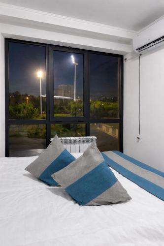 a bedroom with a bed with blue and gray pillows at River guest house in Osh