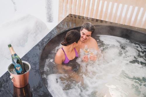 a man and a woman in a bathtub with champagne at Wilderness Hotel Saariselkä in Saariselka