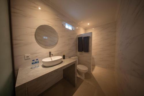 a bathroom with a sink and a toilet and a mirror at Eva Guest House in Canggu