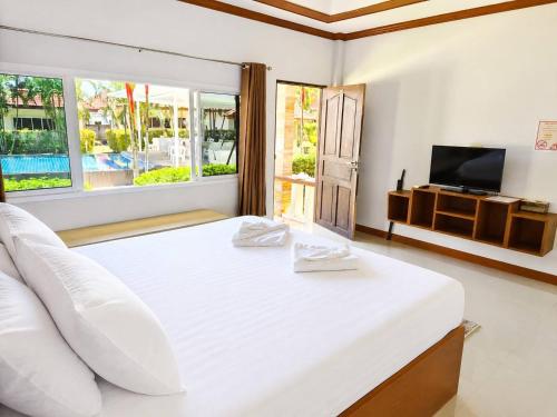 a white bedroom with a large bed and a television at Phuket Airport Villa in Phuket
