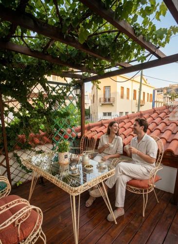 a man and woman sitting at a table on a patio at Apeiron Acropolis Suites by HC in Athens