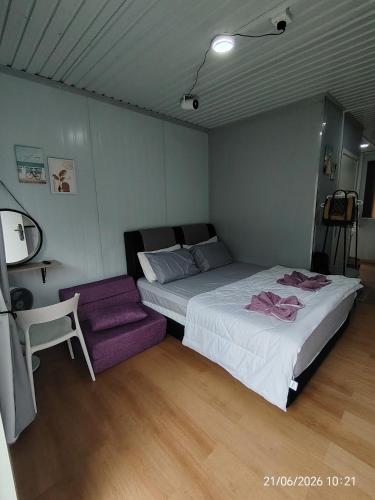 a bedroom with a large bed and a purple chair at DMaro Cabin in Kampong Kundassan