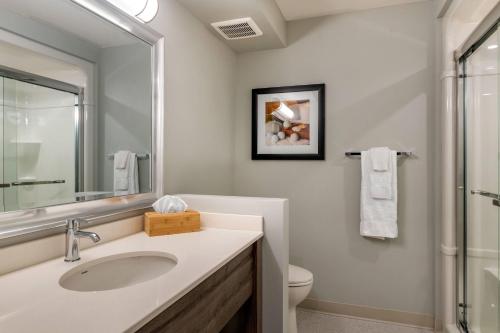 a bathroom with a sink and a toilet and a mirror at Amsterdam Inn & Suites, an Ascend Collection Hotel in Fredericton