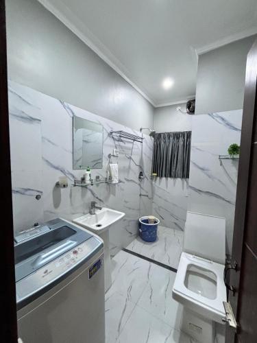 a white bathroom with a sink and a toilet at Unique Nest Homestay in Guwahati