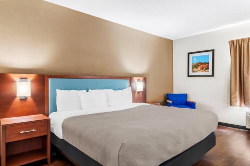 a hotel room with a large bed and a blue chair at Quality Inn Laredo - Nuevo Laredo in Laredo