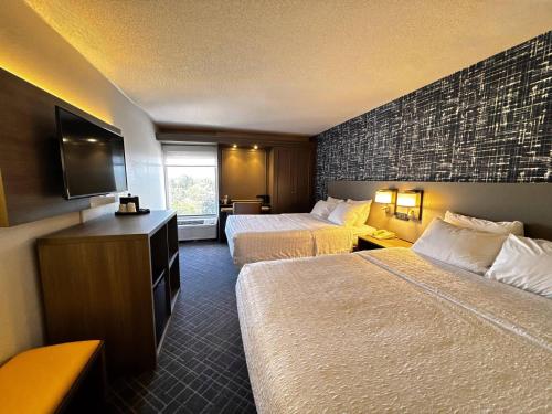 a hotel room with two beds and a flat screen tv at Pittsburgh Airport Inn and Suites in Coraopolis