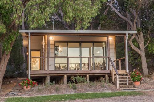 a small house with glass windows and trees at Lake View Cottage in Metricup