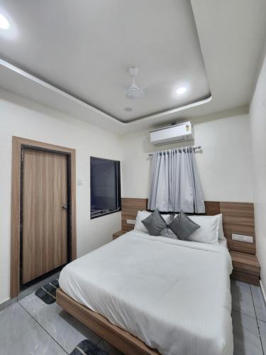 a bedroom with a large white bed with a television at Hotel Namaste Ac Rooms in Vadodara