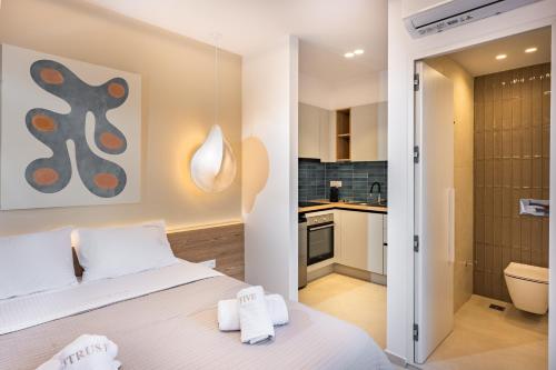 a bedroom with a white bed and a kitchen at Citrus 5 Urban Studios in Mastambás