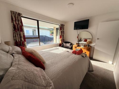a bedroom with a large bed with a large window at B&B on Hoffman in Hokitika