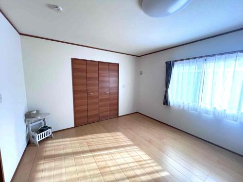 an empty room with a wooden door and a window at すずめのとまりぎ in Nasu