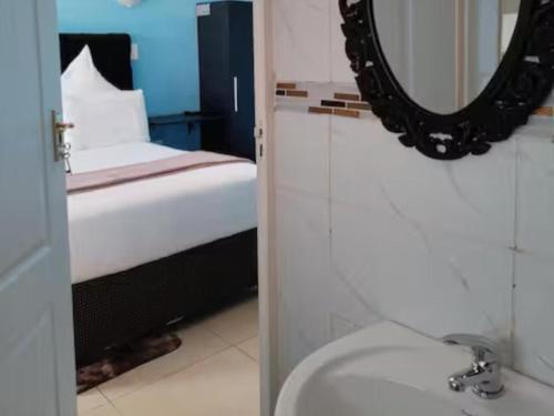 a bathroom with a bed and a mirror and a sink at Zamdu Lodge in Nkandla