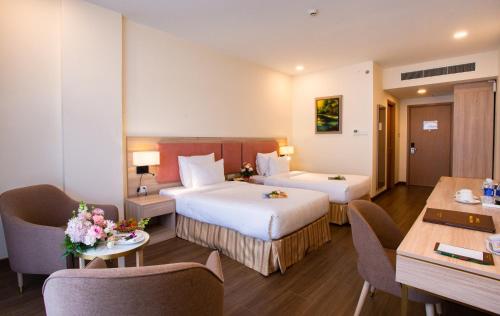 a hotel room with two beds and a table and chairs at Sai Gon Da Lat Premium in Da Lat