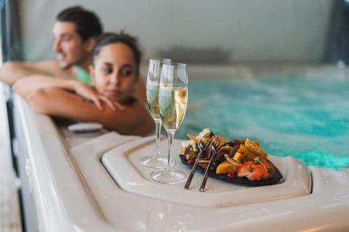 a couple in a swimming pool with a plate of food and wine glasses at Wilderness Hotel Juutua in Inari