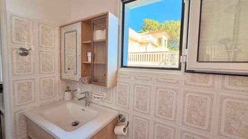 a bathroom with a sink and a window at Avlakia Sunrise Haven Studios in Avlákia