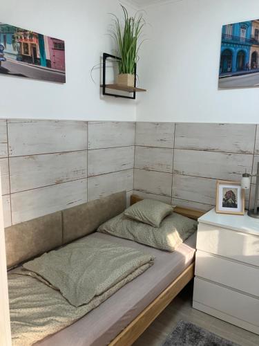 a bed in a room with a wooden wall at Móra apartman 3. in Kiskunfélegyháza