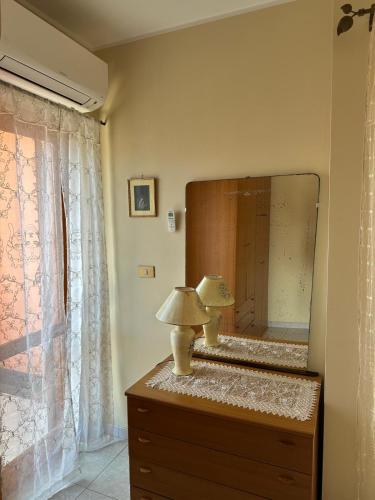 a mirror on top of a dresser with a lamp at Casa Le Araucarie in Mascali