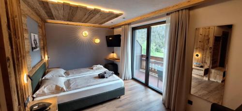 a bedroom with a bed and a large window at Garni Hotel Residence Diamant in San Vigilio Di Marebbe