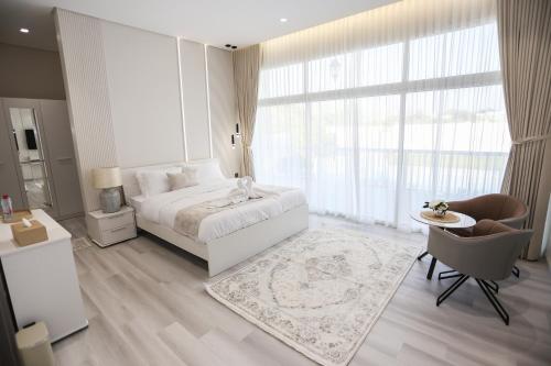 a white bedroom with a bed and a table and chairs at paradise resort and spa in Hatta