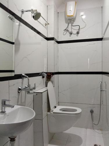 a white bathroom with a toilet and a sink at Aditya Residency, Bhagalpur in Barāri