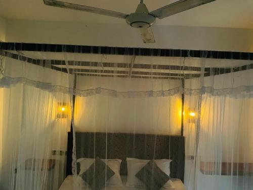 a bedroom with a bed with white curtains and a ceiling at Sky Mountain Café with seaview in Weligama