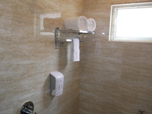 a bathroom with a soap dispenser on the wall at Surendra Landmark By Spree Hotels Bhopal in Bhopal