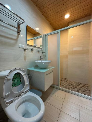 a bathroom with a toilet and a sink and a shower at Yixiangjing Guesthouse in Zhushan