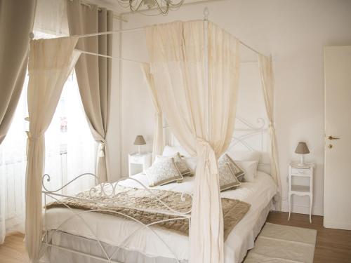 una camera bianca con letto a baldacchino e tende di Tisserand Boutique & Apartment a Lido di Ostia