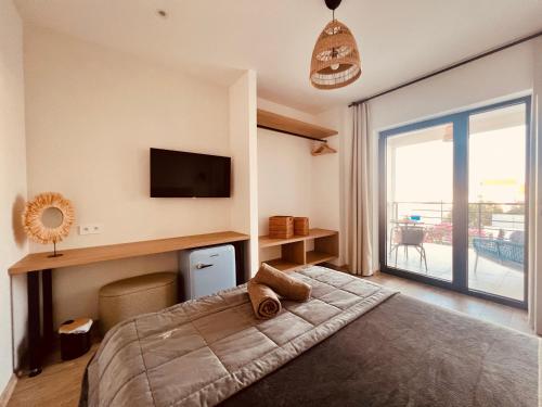 a bedroom with a bed with a television and a balcony at Vila Esnella - Private Pool & Panoramic Sea view in Primošten