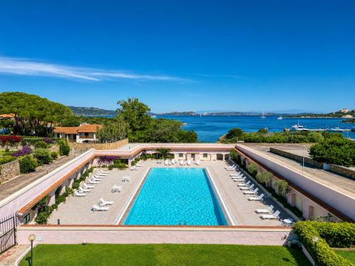 an aerial view of a pool with lounge chairs and the water at Baja Sardinia Sea View And Pool B in Baja Sardinia