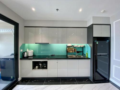 a kitchen with green and white cabinets and a refrigerator at Amanda Apartment Quy Nhon in Quy Nhon
