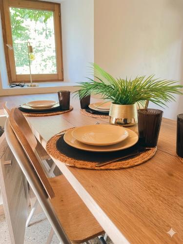 a dining room table with plates and plants on it at Petite maison ardéchoise in Saint-Michel-de-Chabrillanoux