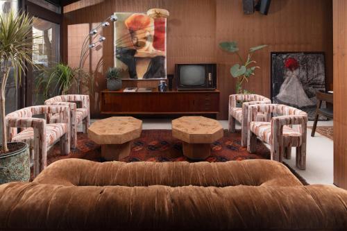 a living room with a couch and chairs and a tv at Theodor Rothschild Tel-Aviv in Tel Aviv